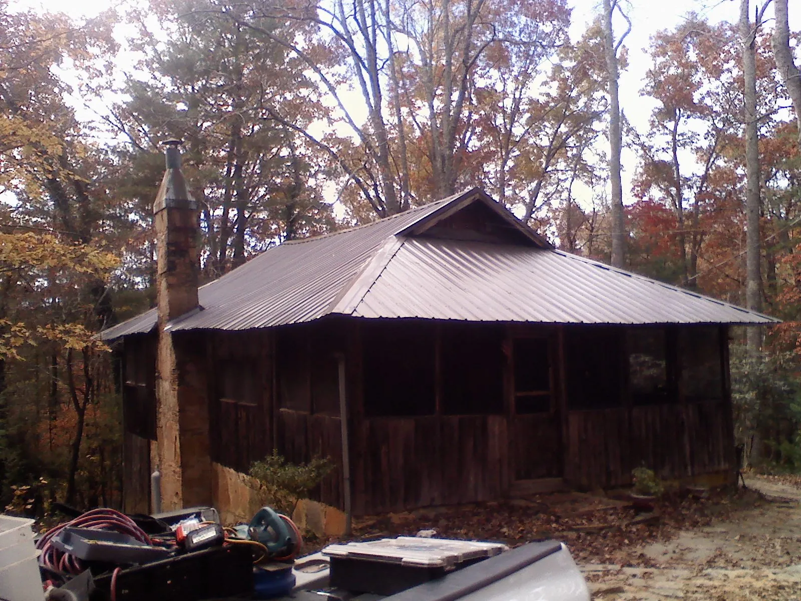 Brown metal hip roof on an old cabin with a stone chimney in Auburn